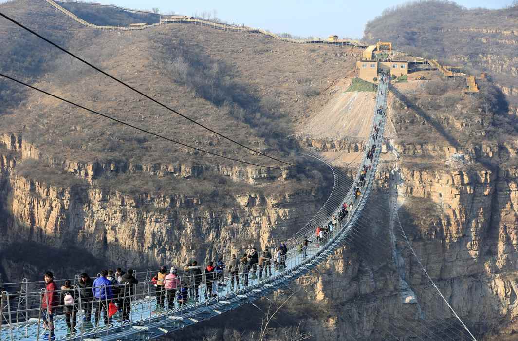 SCENIC WALK: Visitors walk on the newly-opened 488-metre-long glass suspension bridge at Hongyagu attraction in Pingshan, Hebei province, China, Zhang Haiqiang/Reuters/UNI